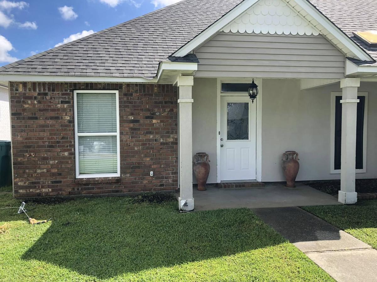 Before: a one-story house in dark red-brown brick with a covered porch and a white door