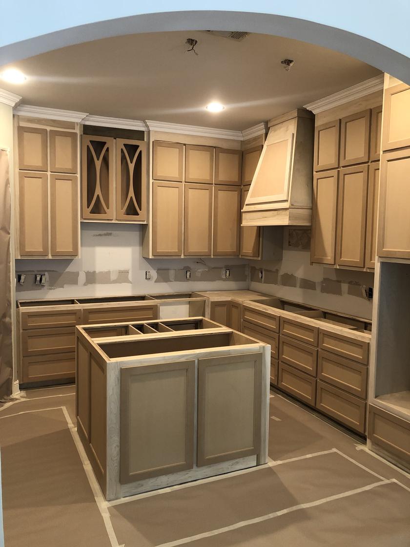 Before: a new kitchen with raw wood cabinets and builder's paper on the floor