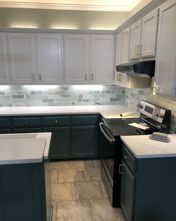 A two-tone kitchen with white uppers, teal lowers and brass hardware