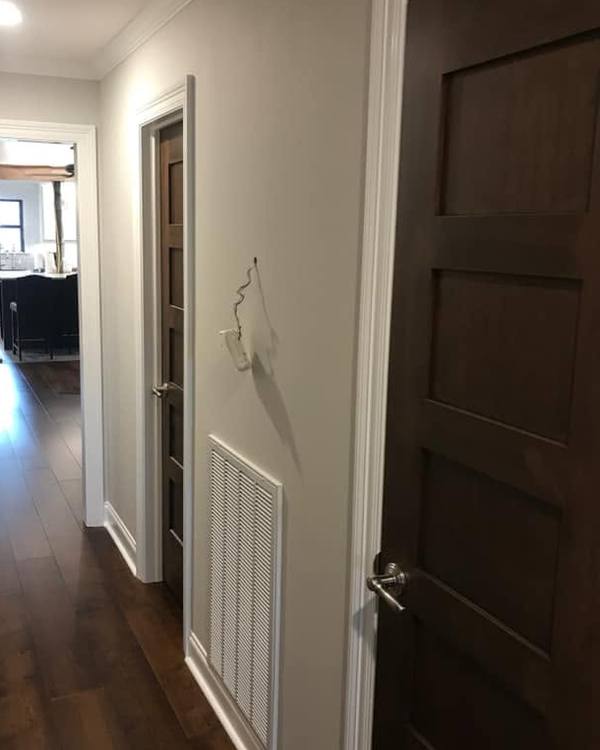 A hallway in light grey with white trim and dark stained doors