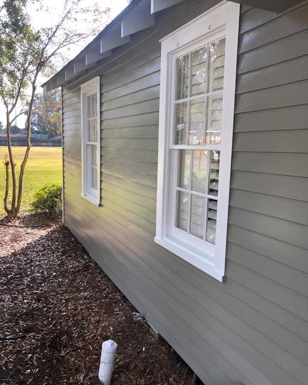 Lap siding painted sage green with white window casings