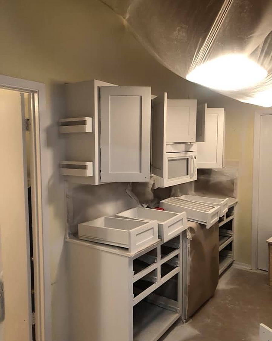 Cabinet doors sprayed white, with the room masked in plastic