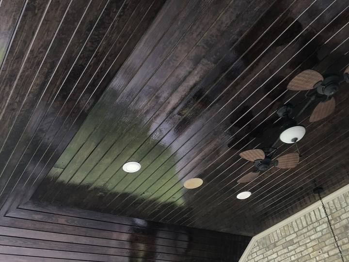 A covered patio ceiling of tongue-and-groove boards stained dark walnut