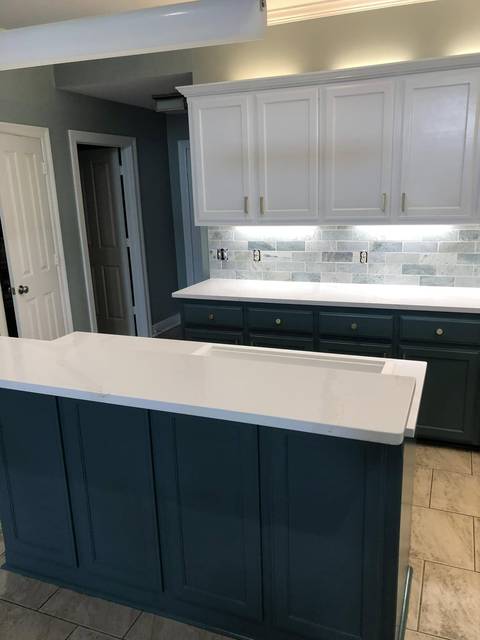 A kitchen with white uppers, teal lowers and a teal island