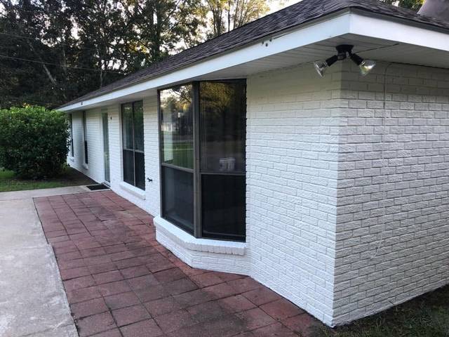 A front walk and bay window on a white-painted brick house
