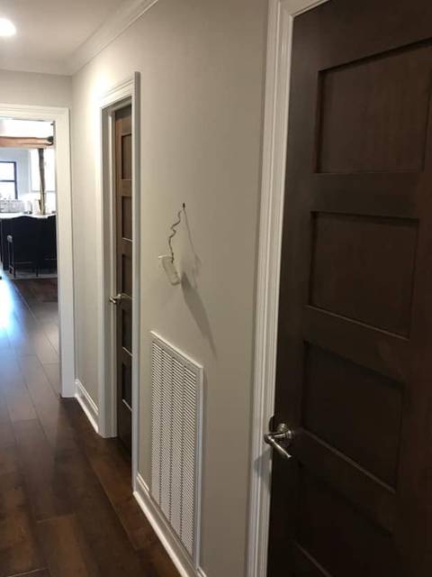 A hallway in light grey with white trim and dark stained doors