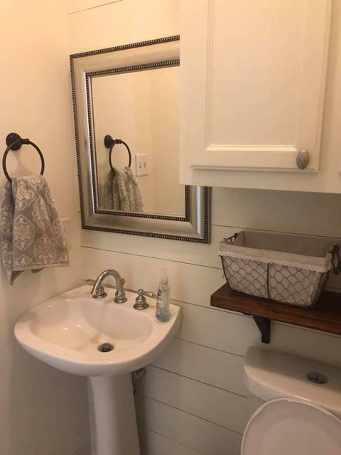 A half bath with white shiplap and a stained wood shelf