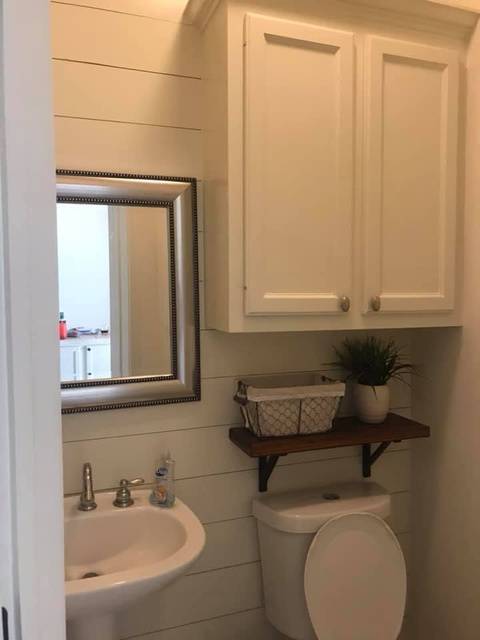 A half bath, wider: shiplap, a cabinet and a framed mirror