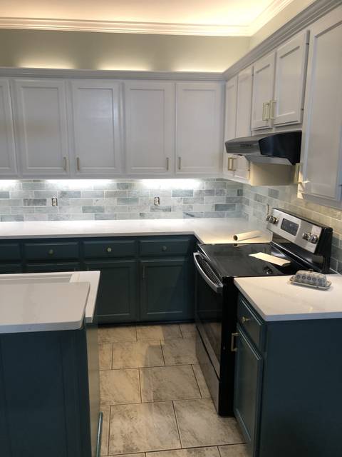 A two-tone kitchen: white uppers, teal lowers, brass hardware