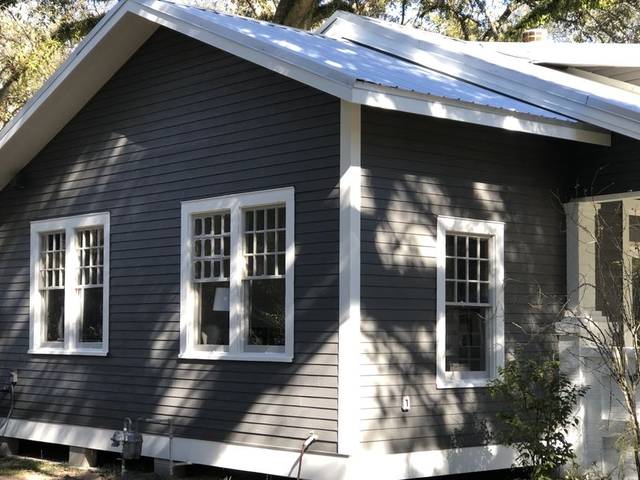 A house corner in charcoal lap siding with white trim and a standing-seam metal roof