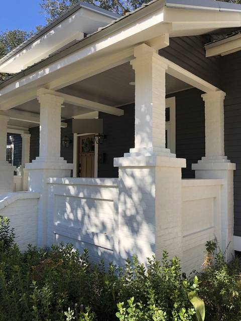 A bungalow porch with white tapered columns on brick piers