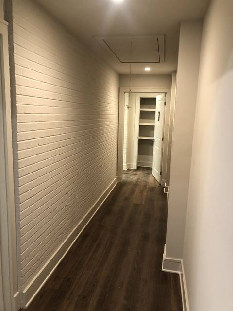A hallway with a whitewashed brick accent wall and a plank floor