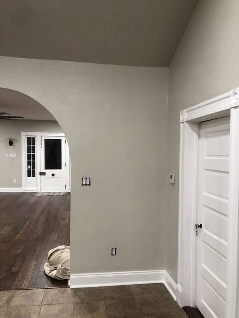 A room with a vaulted greige ceiling and an archway to the room beyond