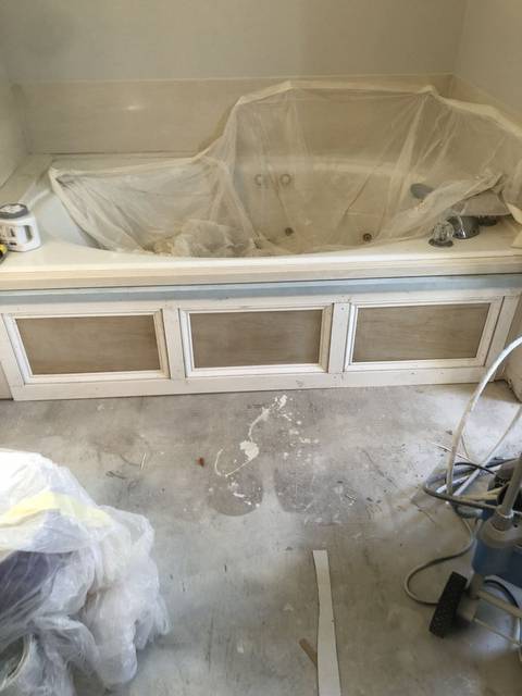 A garden tub apron mid-refinish, stripped and sanded under masking plastic