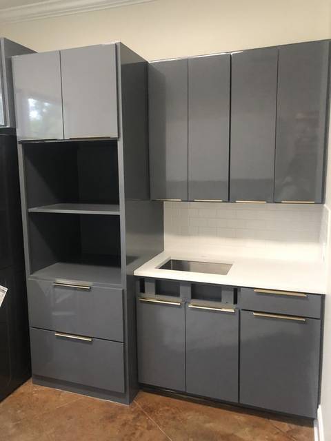 High-gloss grey flat-panel cabinets with brass hardware and a white subway backsplash