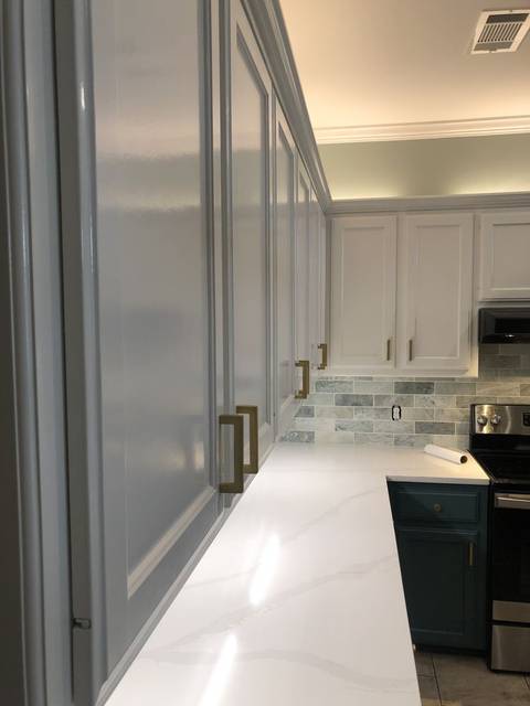 Tall slate-blue cabinets with brass bar pulls under white uppers