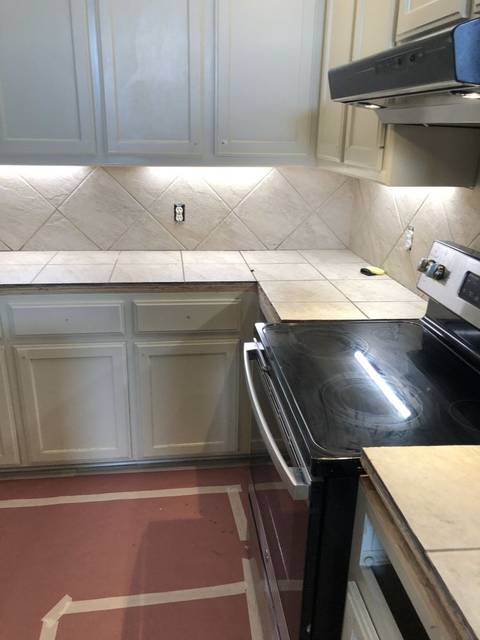 An old kitchen before a cabinet refinish: tile counters and a taped floor